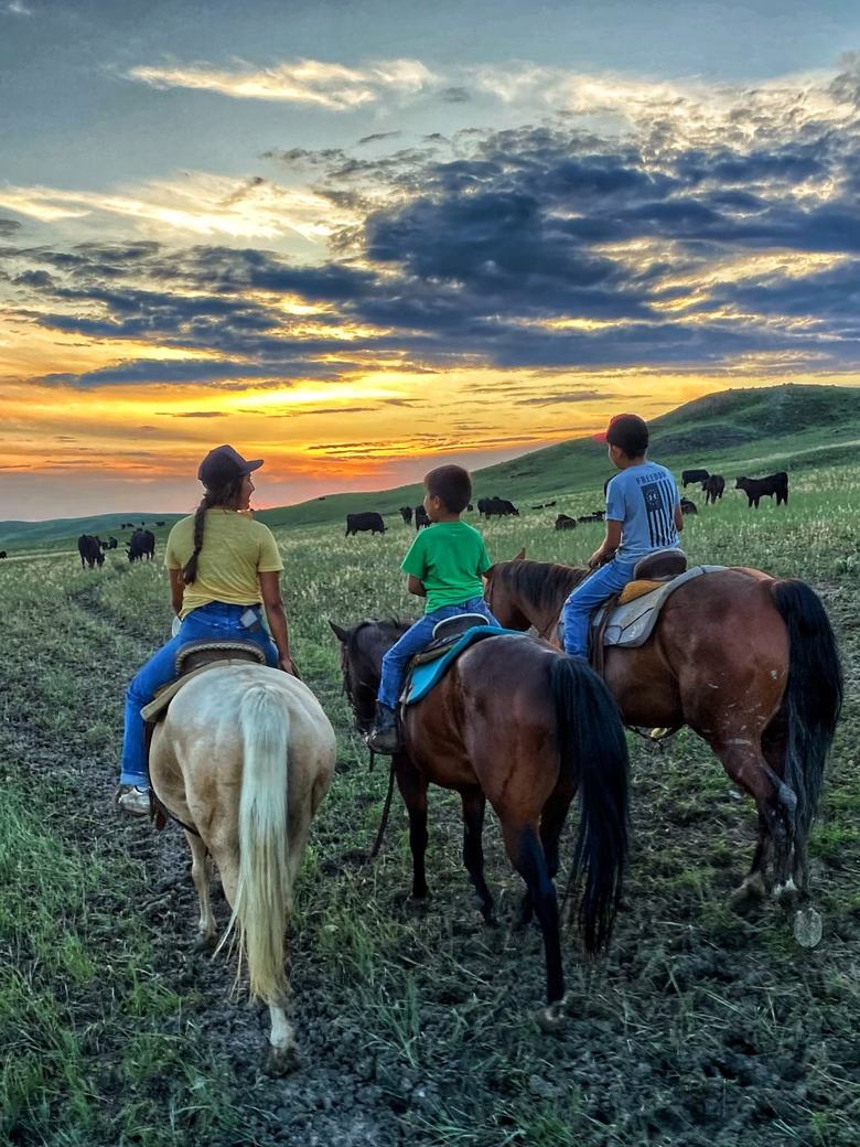 Riders on horseback at sunset on a South Dakota ranch