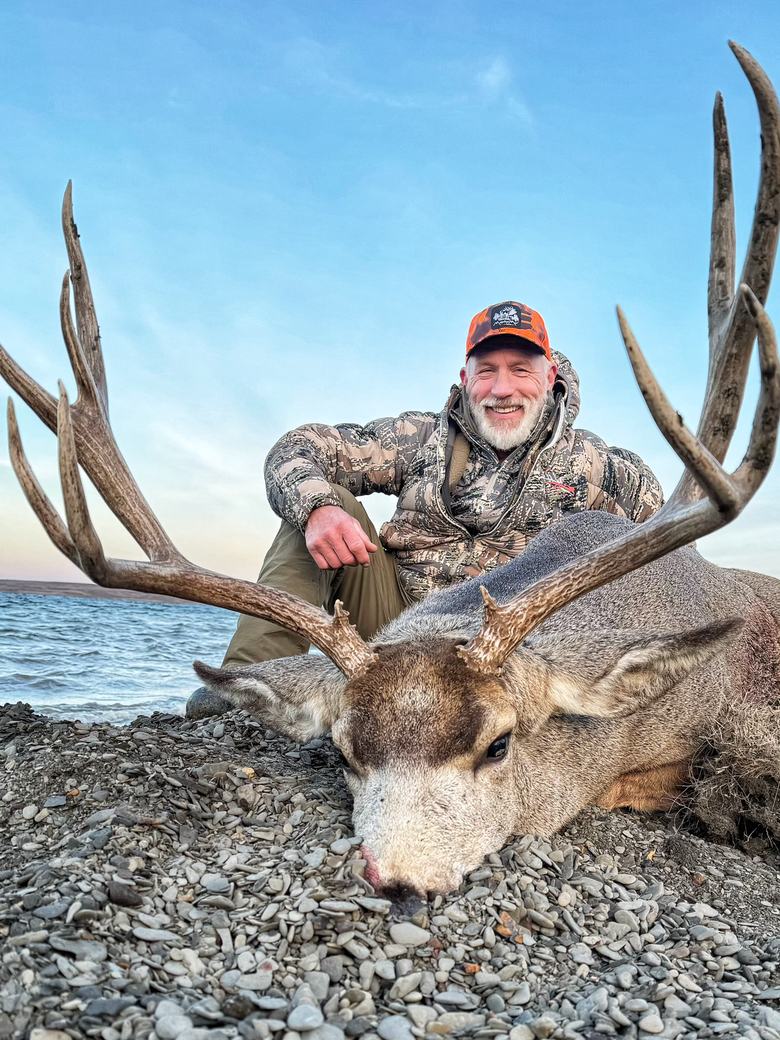 Hunter holding the wide rack of a mature mule deer buck