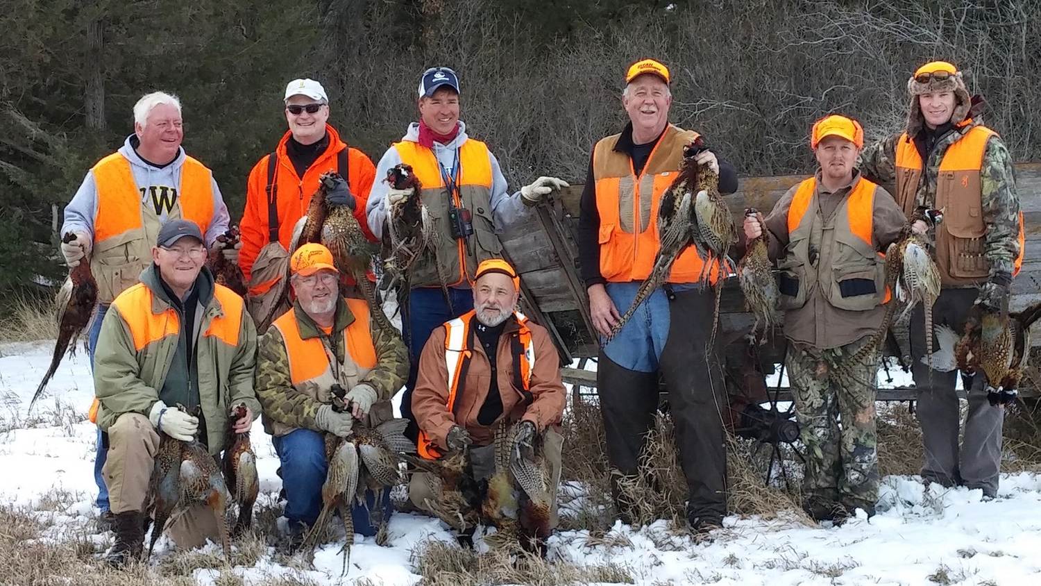 Group of hunters with a limit of pheasants in a snowy field