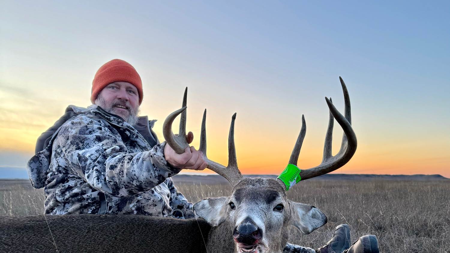 Hunter with a whitetail buck at sunset in South Dakota