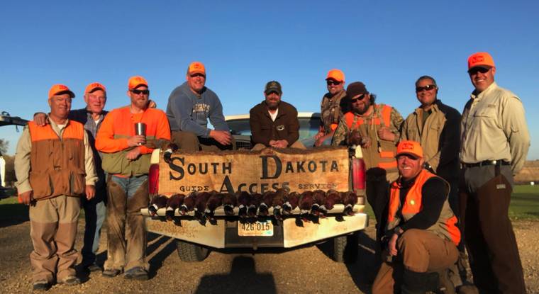 Hunting party with a limit of roosters behind the South Dakota Access sign