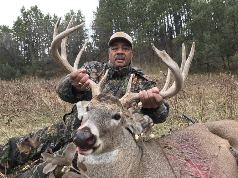 Hunter holding the antlers of a heavy-beamed mule deer buck