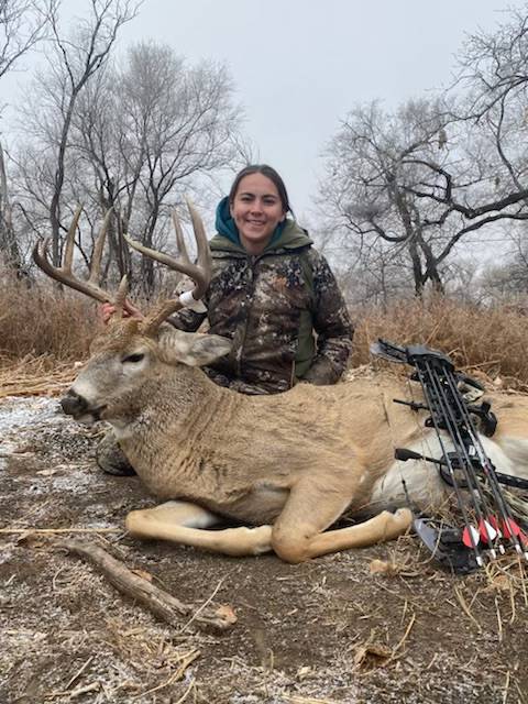 Archery hunter beside a whitetail buck on a South Dakota private ranch