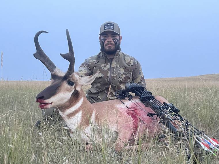Hunter with a pronghorn buck in native prairie grass