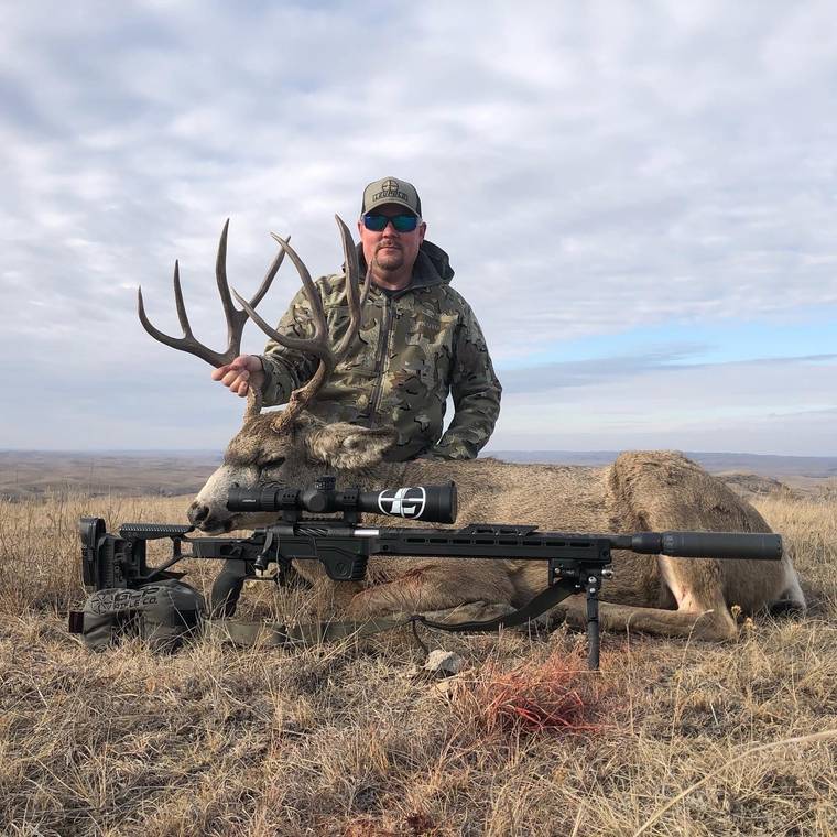 Rifle hunter behind a heavy mule deer buck taken off a bipod