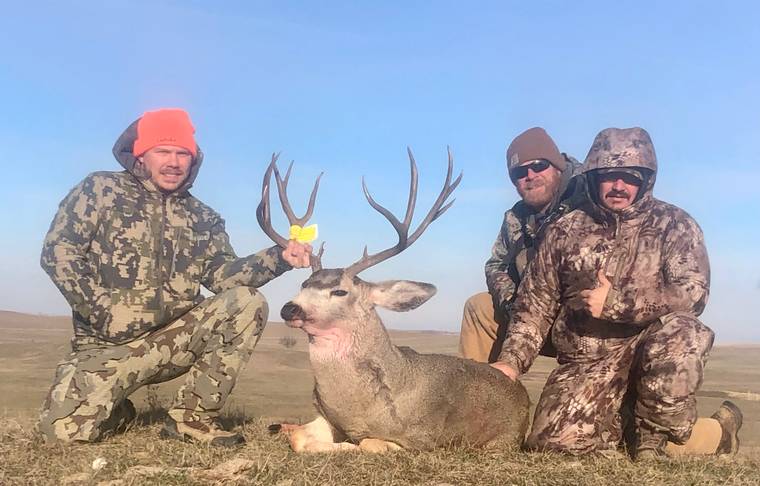 Two hunters with a mule deer buck in a South Dakota draw