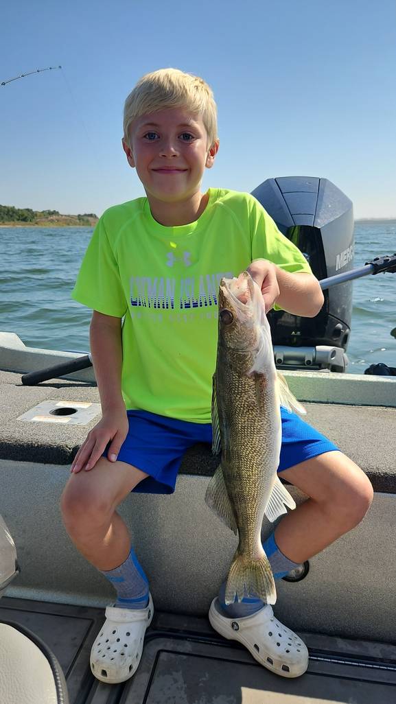 Young angler holding a Missouri River walleye aboard the boat