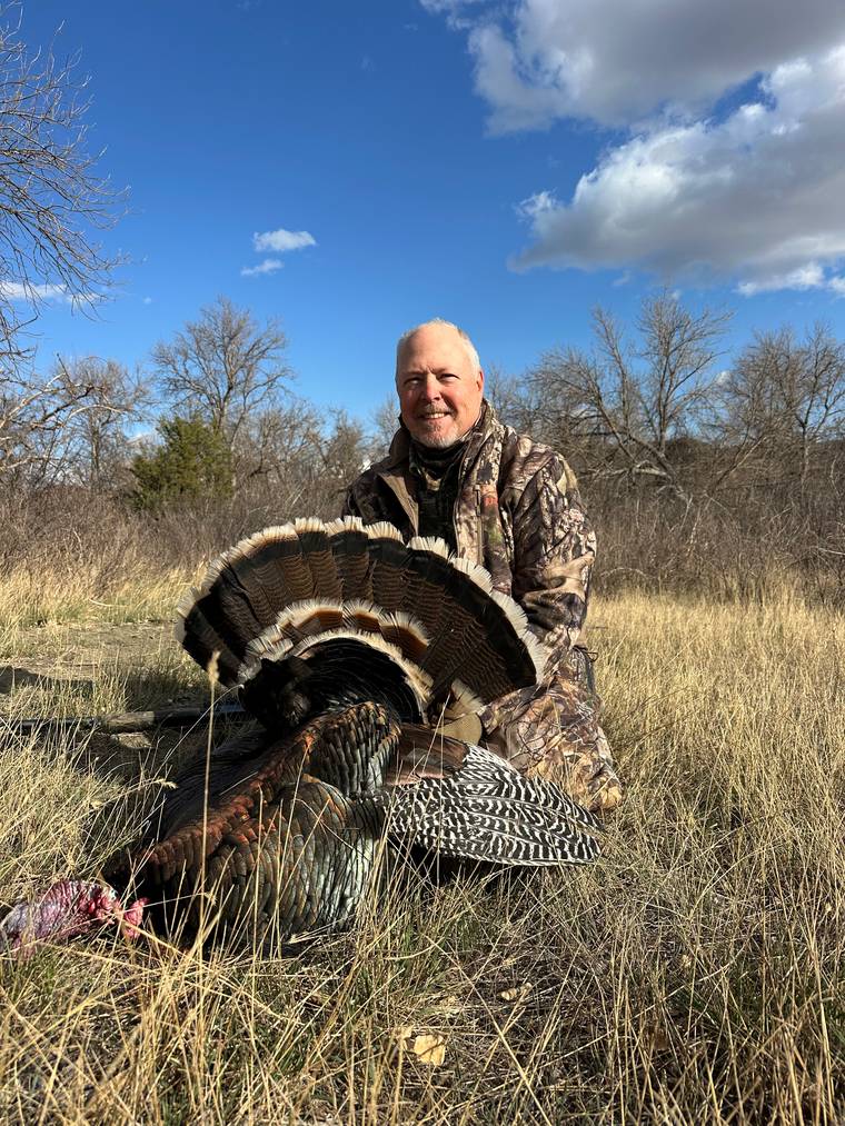 Hunter fanning the tail of a harvested Merriam's turkey