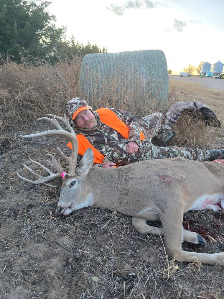 Hunter with a whitetail buck in a snow-covered field